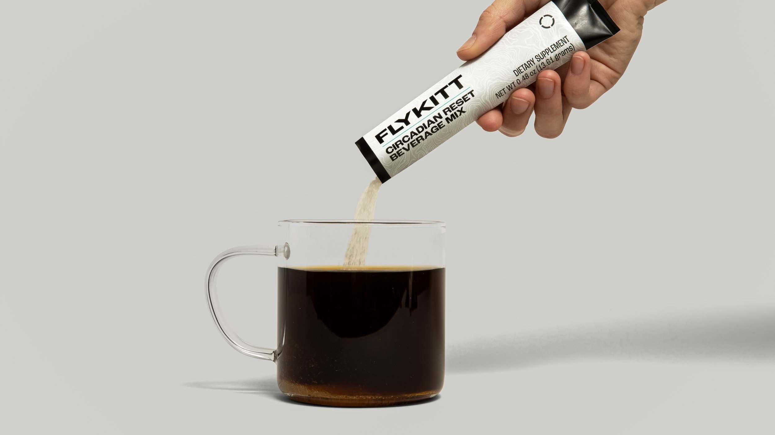 Pouring FlyKitt Circadian Reset mix into a glass of coffee